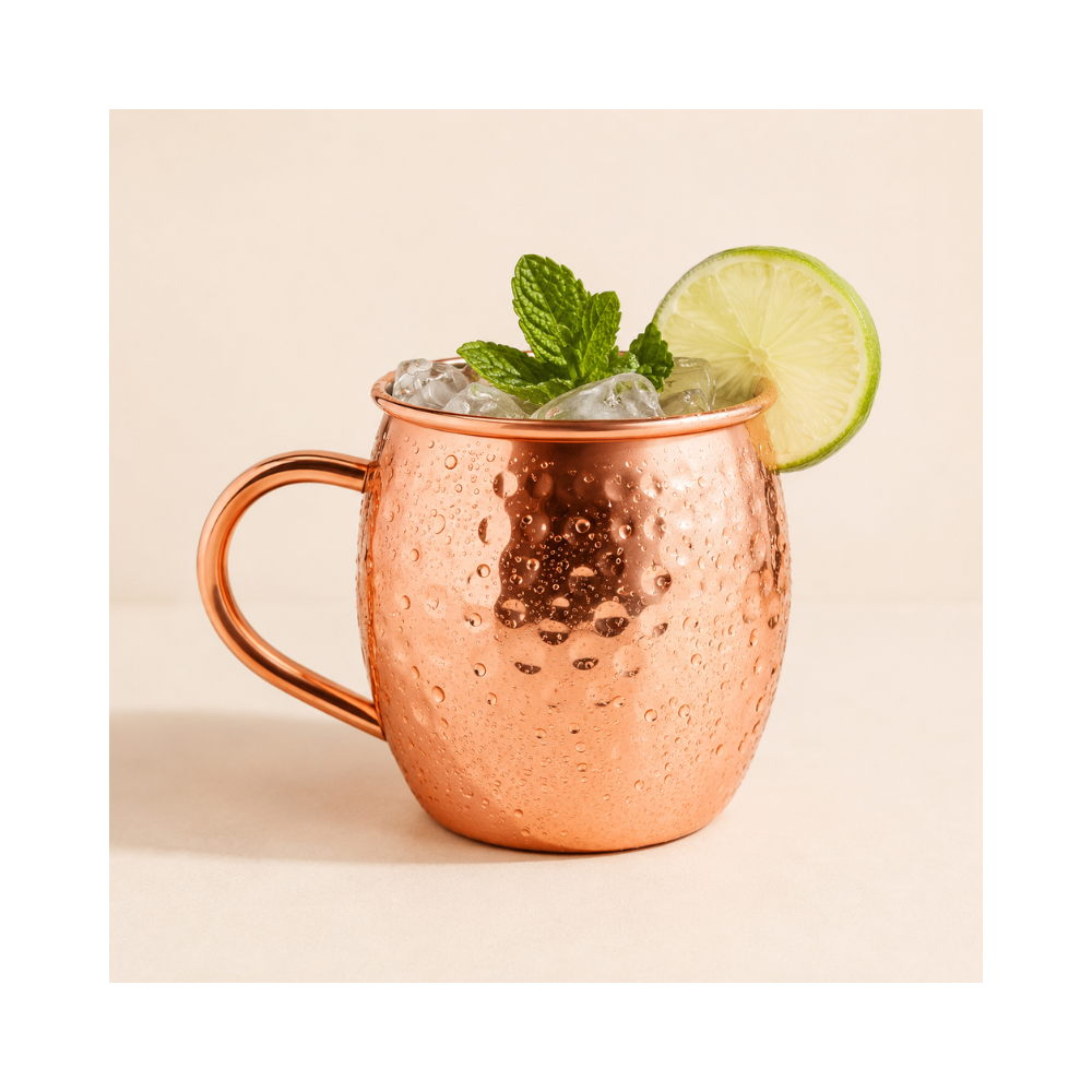 Caneca Moscow Mule de cobre com bebida gelada, gelo, limão e folhas de hortelã, ideal para drinks e coquetéis.