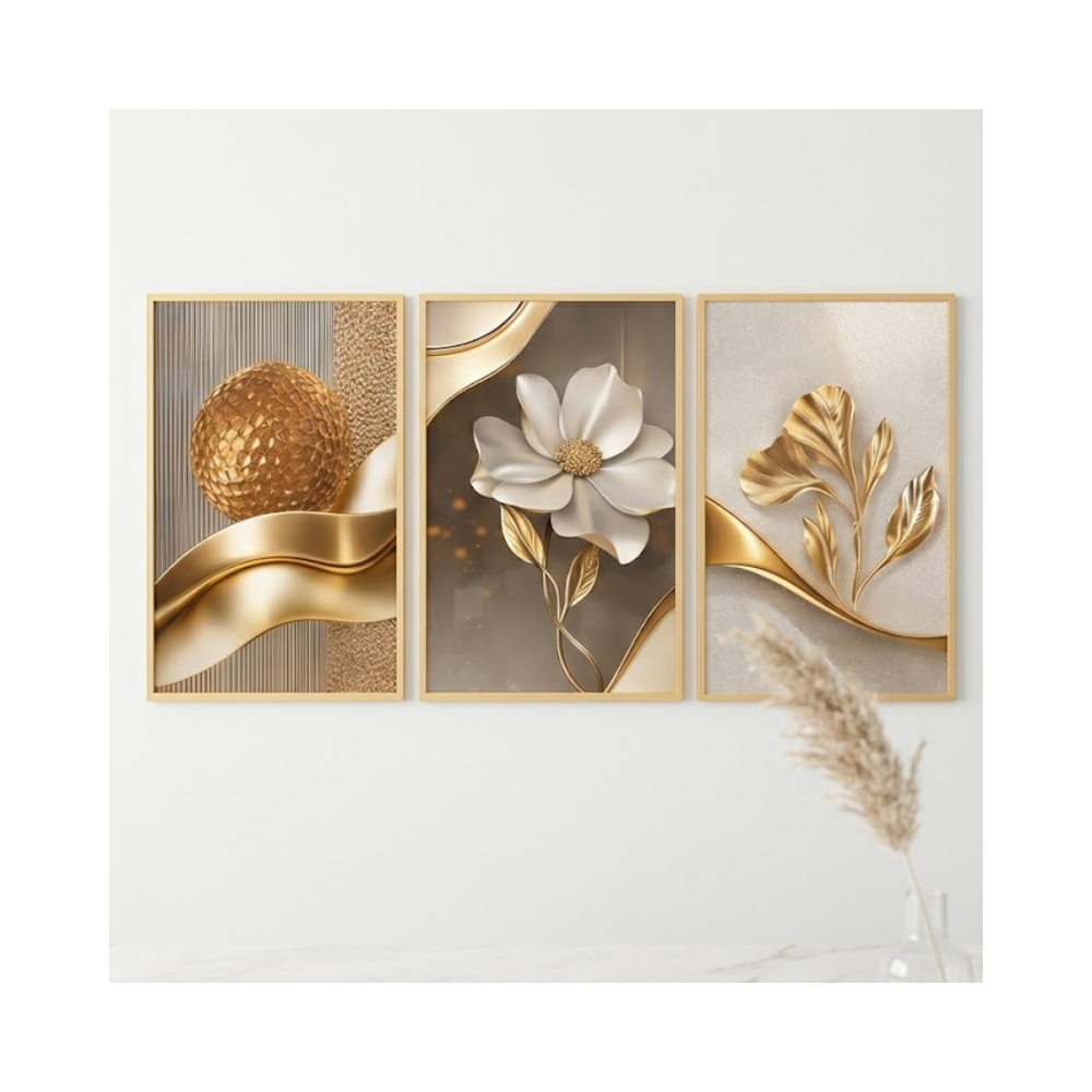 Fotografia em estilo clean e minimalista com fundo branco luminoso, exibindo um conjunto de três quadros decorativos com moldura fina dourada, alinhados horizontalmente. As artes apresentam um design contemporâneo luxuoso em tons de dourado, champagne e branco, com elementos texturizados que simulam relevo: o primeiro quadro traz formas abstratas e uma esfera dourada, o central destaca uma flor majestosa com miolo reluzente, e o terceiro exibe folhas minimalistas douradas. Na parte inferior, uma superfície de mármore claro reflete suavemente os quadros, decorada apenas com um vaso de vidro transparente contendo um ramo de capim-dos-pampas, criando uma atmosfera elegante, clean e clean.