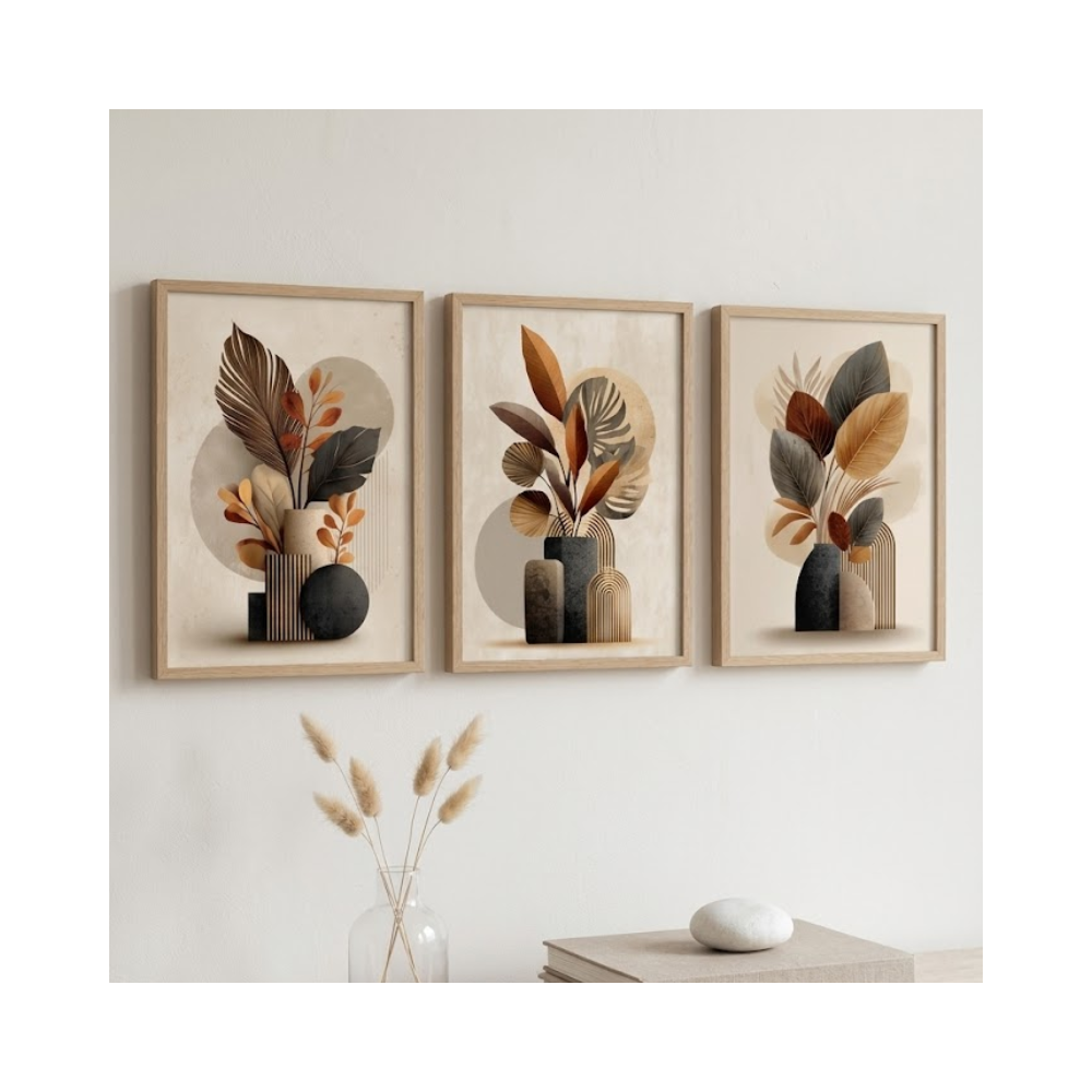 Conjunto de três quadros decorativos com moldura de madeira clara, dispostos horizontalmente em uma parede cinza texturizada com iluminação natural lateral. As artes apresentam ilustrações abstratas e minimalistas de vasos modernos com arranjos de folhas secas, costela-de-adão e ramagens em uma paleta elegante de tons terrosos, preto, bege e ocre, transmitindo uma estética boho chic e escandinava.